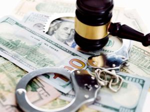 handcuffs and gavel on top of a pile of money
