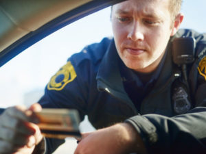 a police offer looks at a drivers license during a traffic stop