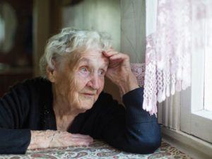 a photo of an elderly woman looking out a window